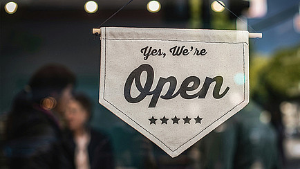 Ein Wimpel vor einem Fenster mit der Aufschrift: Yes, we're open. Darunter fünf Sterne.