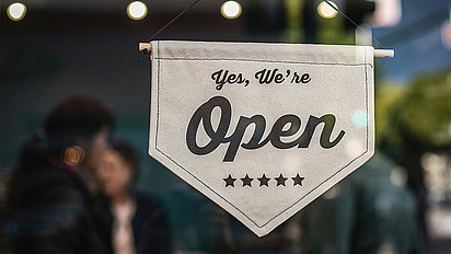 Ein Wimpel vor einem Fenster mit der Aufschrift: Yes, we're open. Darunter fünf Sterne.