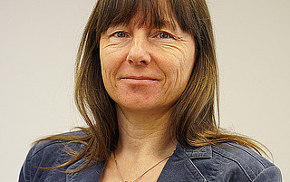 Portraitfoto von Christine Hennig vor grauem Hintergrund