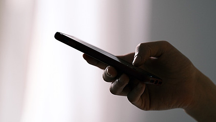 Eine Hand mit einem Smartphone, die Person tippt eine Nachricht ein.