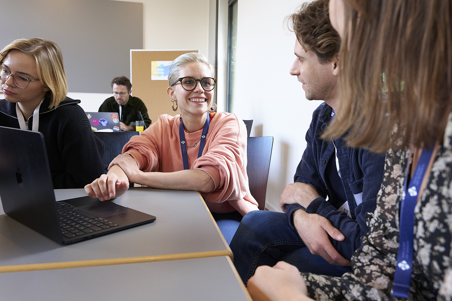 Personen im Gespräch an einem Laptop, sie tragen Lanyards der GI