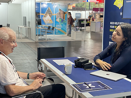 Elena Müller and Ralf Möller sitting at a table across from each other talking