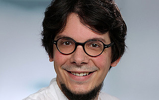 Portraitfoto von Prof. Dr. Alexander Steen vor grauem Hintergrund