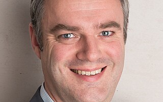 Portraitfoto von Dr. Michael Räckers vor grauem Hintergrund